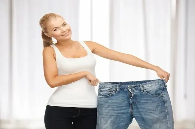 A woman is holding her jeans and smiling