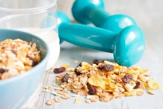 A bowl of cereal and two blue dumbbells